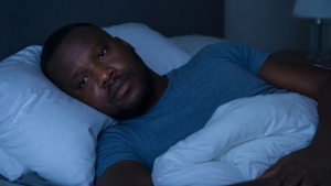 person lying in bed at night awake and aware